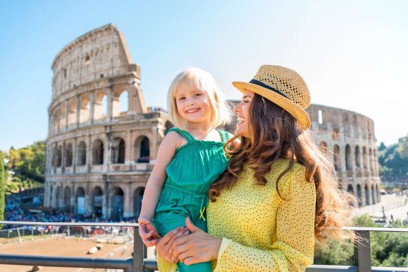 Mother and daughter smiling in front of the Colosseum, Rome, Italy